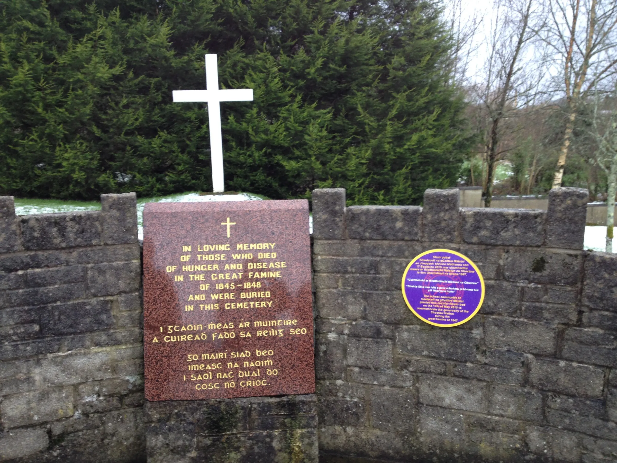 A stone enclosure with a white cross and a memorial plaque to the Famine dead