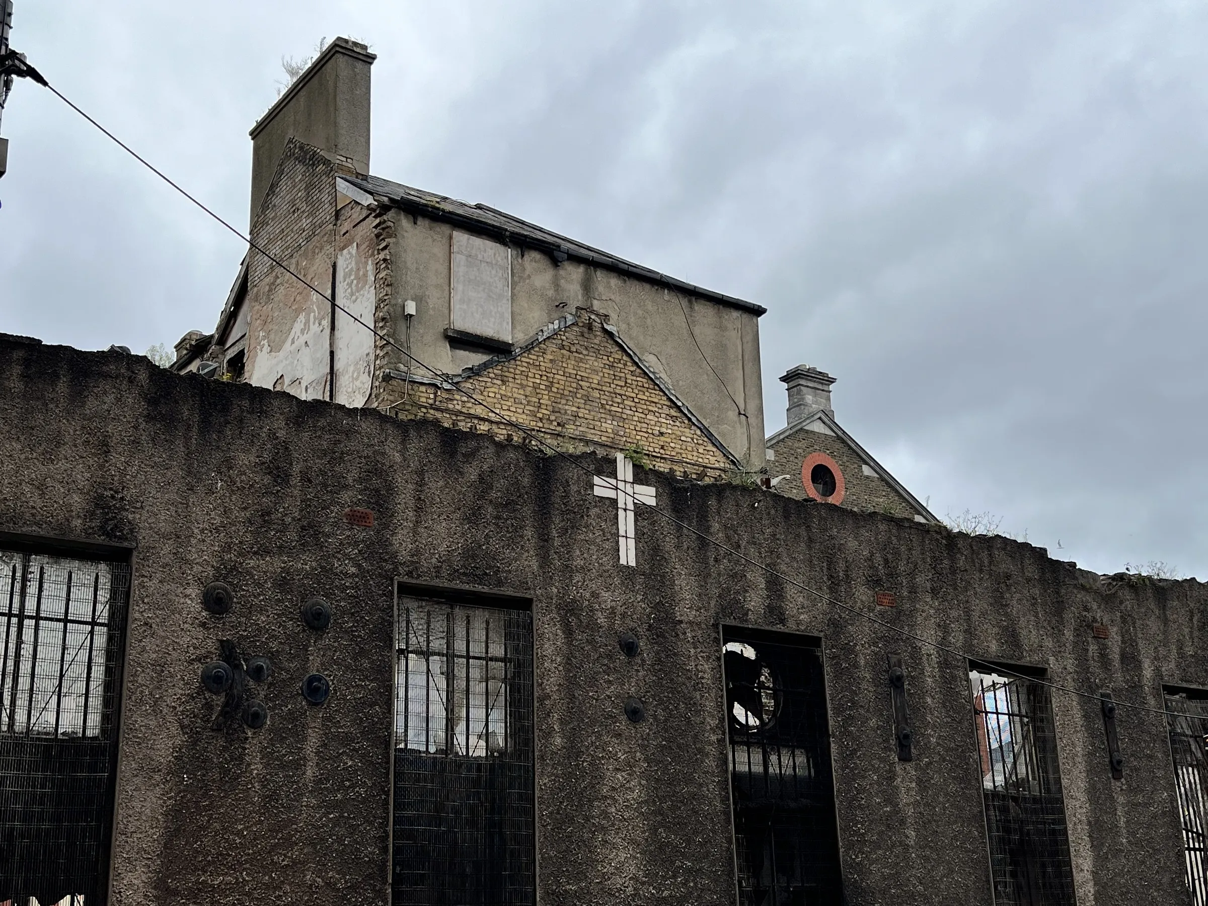 A roofless stone building, a white cross fixed to the gable