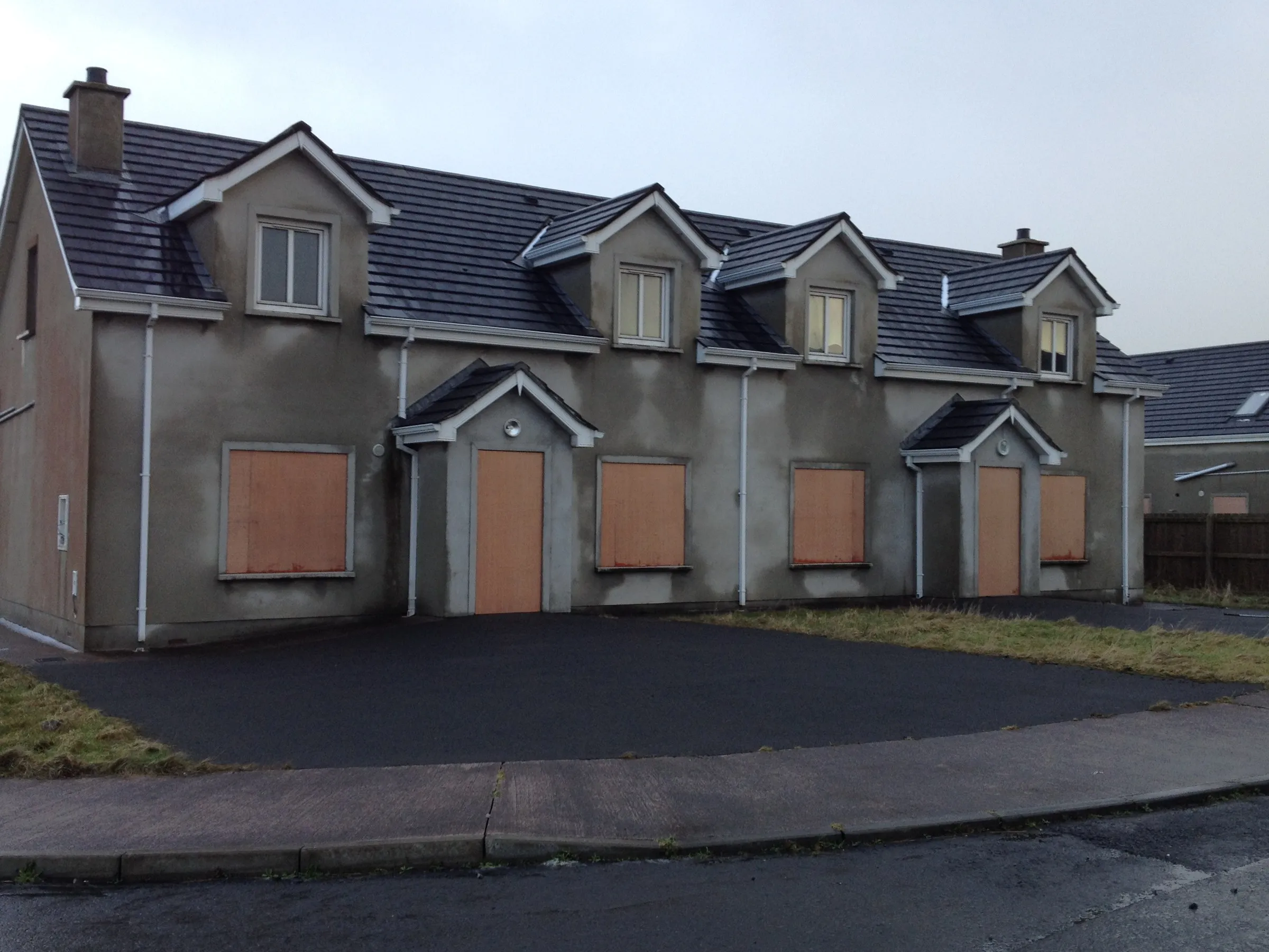 A terrace of new houses with every opening boarded in orange