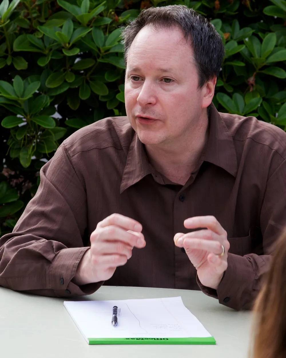 Gavin Keulks talking across a table, an open notepad and pen in front of him